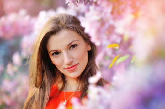 Portrait of pretty woman near the blossomed tree in the park. Concept of youth and natural beauty