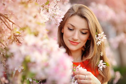 Portrait of beautiful woman near a flowering tree.