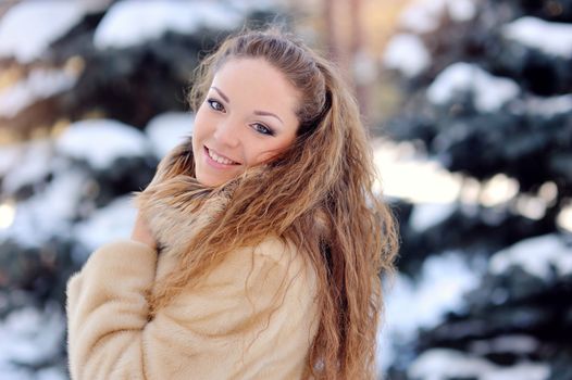 beautiful woman on the street near fir-tree in winter.