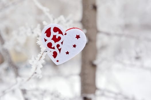red heart toy on tree with snow and icicle.