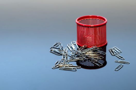 Red iron pot and heap of paper clips. 