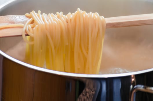 View in a saucepan with a wooden spoon hanging over the spaghetti.
