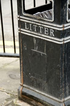 Black litter on the sidewalk in front of road-fence in London.