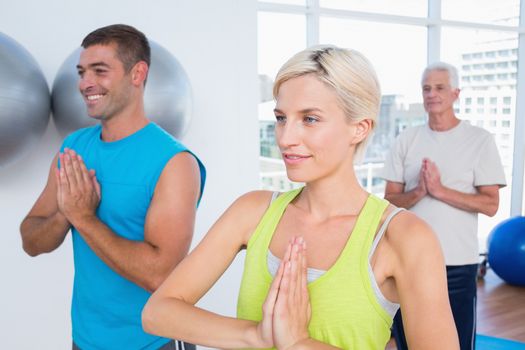 Woman with male friends meditating in fitness club
