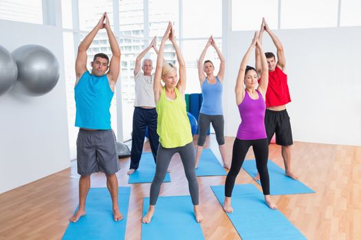 Full length of people doing stretching exercise in yoga class