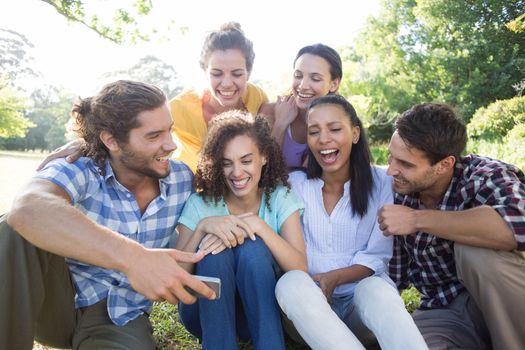 Smiling friends in the park taking selfie on a sunny day