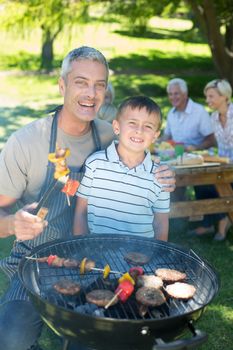 Happy father doing barbecue with his son on a sunny day