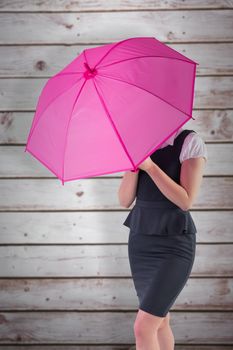Pretty redhead businesswoman holding umbrella against wooden planks