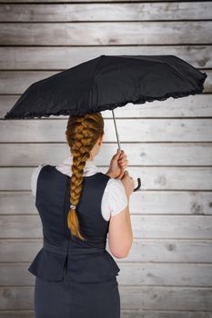 Pretty redhead businesswoman holding umbrella against wooden planks