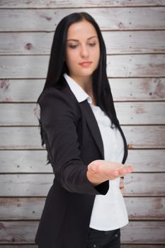 Pretty businesswoman presenting with hand against wooden planks