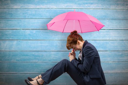 Businesswoman with umbrella against wooden planks