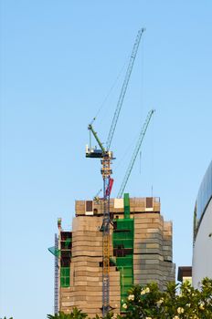 Building and cranes under construction against blue sky 