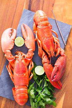 Close up Appetizing Ready to Eat Cooked Lobsters Duo on a Cutting Board with Lime and Parsley, Served on a Wooden Table.