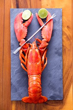 Close up Red Lobster Clipping Lime Slices on a Gray Cutting Board with Picks, Served on Top of a Wooden Table.