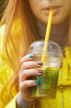 girl is drinking a large glass of lemonade. Close portrait