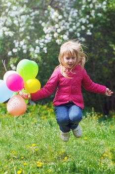 Outdoor portrait of a cute young  little girl jumping with balloons