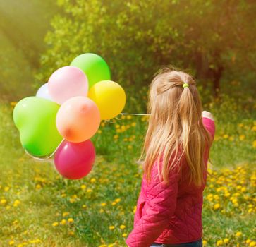 Outdoor portrait of a cute young  little girl Turned back with balloons