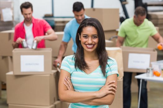 Portrait of a smiling volunteer with arms crossed in a large warehouse