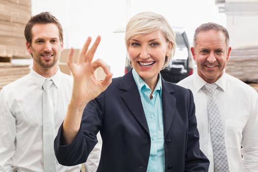 Smiling warehouse manager making okay gesture in a large warehouse