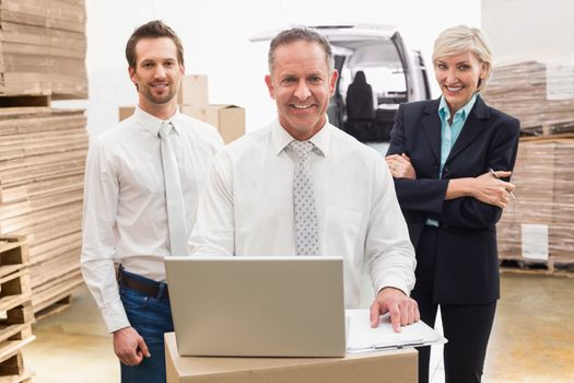 Warehouse team working together on laptop in a large warehouse