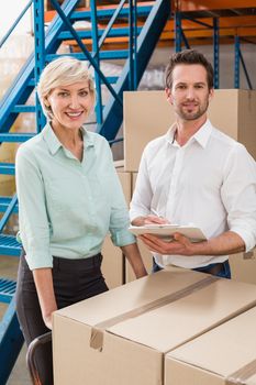 Smiling warehouse managers with clipboard in a large warehouse