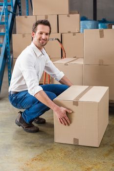 Smiling warehouse manager with box in warehouse