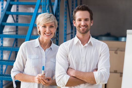 Smiling warehouse managers looking at camera in a large warehouse