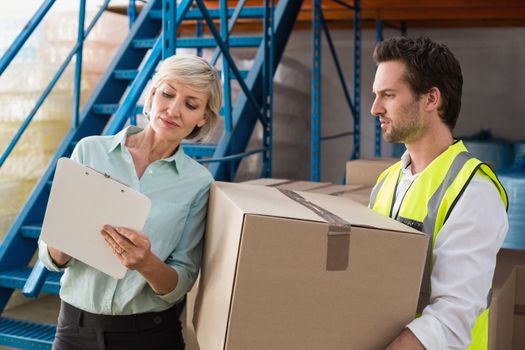 Warehouse manager and worker looking at clipboard in a large warehouse