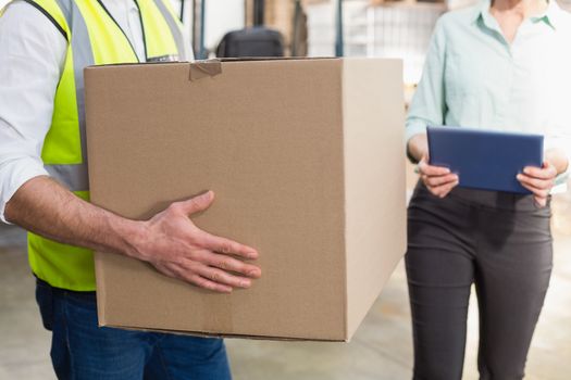Close up of a warehouse worker carrying box in a large warehouse