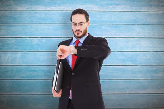 Frowning young businessman checking time against wooden planks