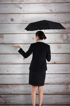 Young businesswoman holding umbrella against wooden planks