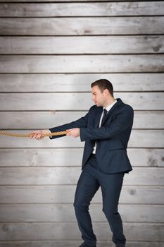 Young businessman pulling a rope against wooden planks