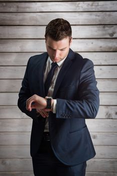 Handsome businessman checking the time against wooden planks