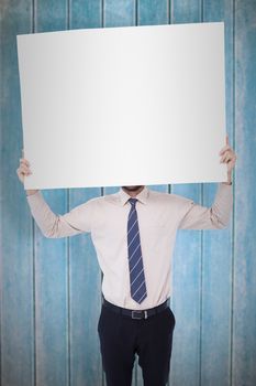 Businessman showing white poster in front of his head against wooden planks