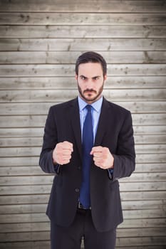 Angry businessman with closed fists looking at camera against wooden planks background