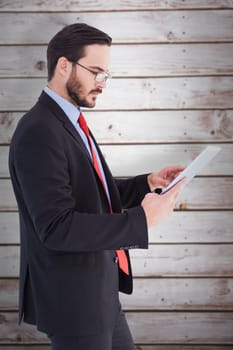 Businessman scrolling on his digital tablet against wooden planks