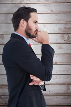 Thinking businessman standing with hand on chin against wooden planks
