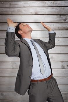 Businessman standing with arms pressing up against wooden planks