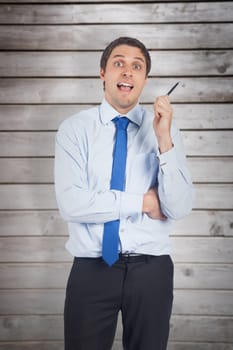 Thinking businessman holding pen against wooden planks