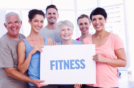 The word fitness against fit people holding blank board in yoga class