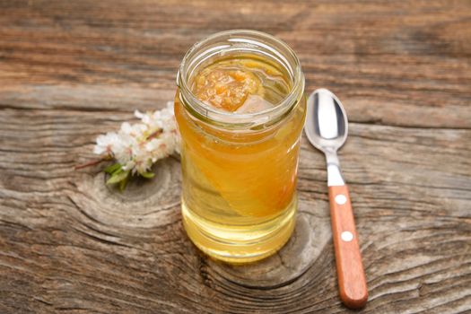 Glass pot full of honey on rustic wooden background
