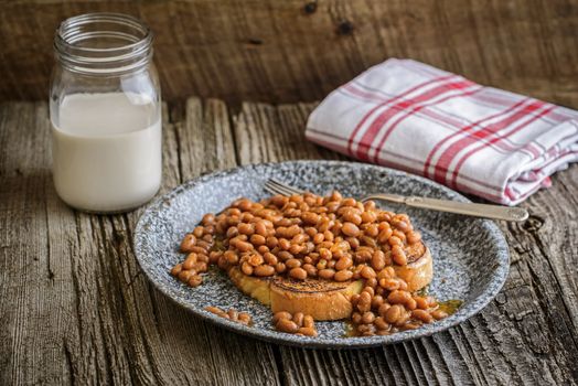 Plate of baked beans with toast on a rustic background.