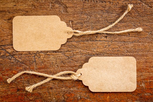 two blank paper price tags with a twine against rustic scratched wood