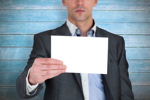 Businessman in grey suit showing card against wooden planks
