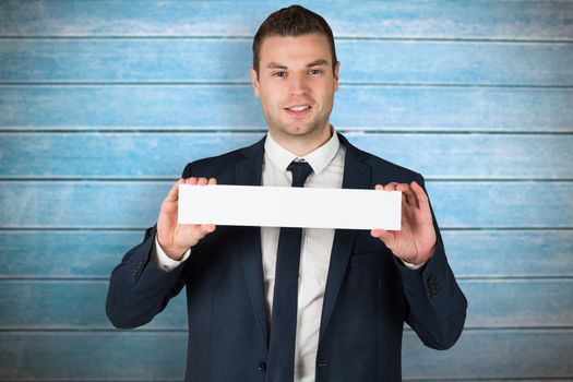 Happy businessman showing card to camera against wooden planks