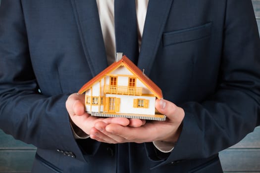 Businessman holding miniature house model against wooden planks