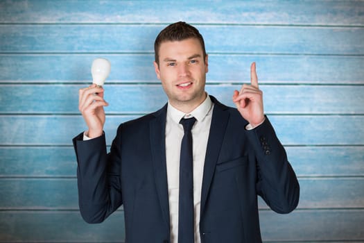 Businessman holding light bulb and pointing against wooden planks