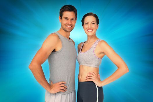 Portrait of a happy fit couple with hands on hips against abstract background