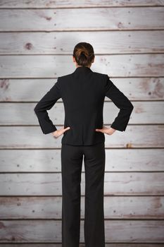 Businesswoman standing with hands on hips against wooden planks