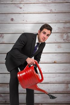 Businessman watering with red can against wooden planks